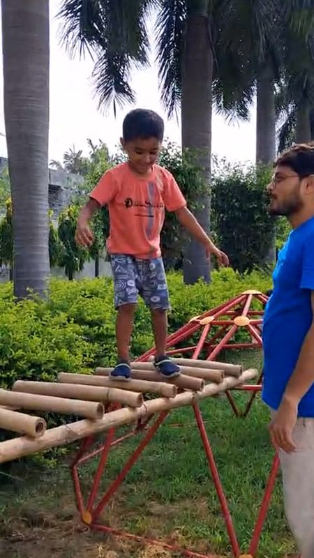 A child balancing along bamboo poles over the climbing dome.