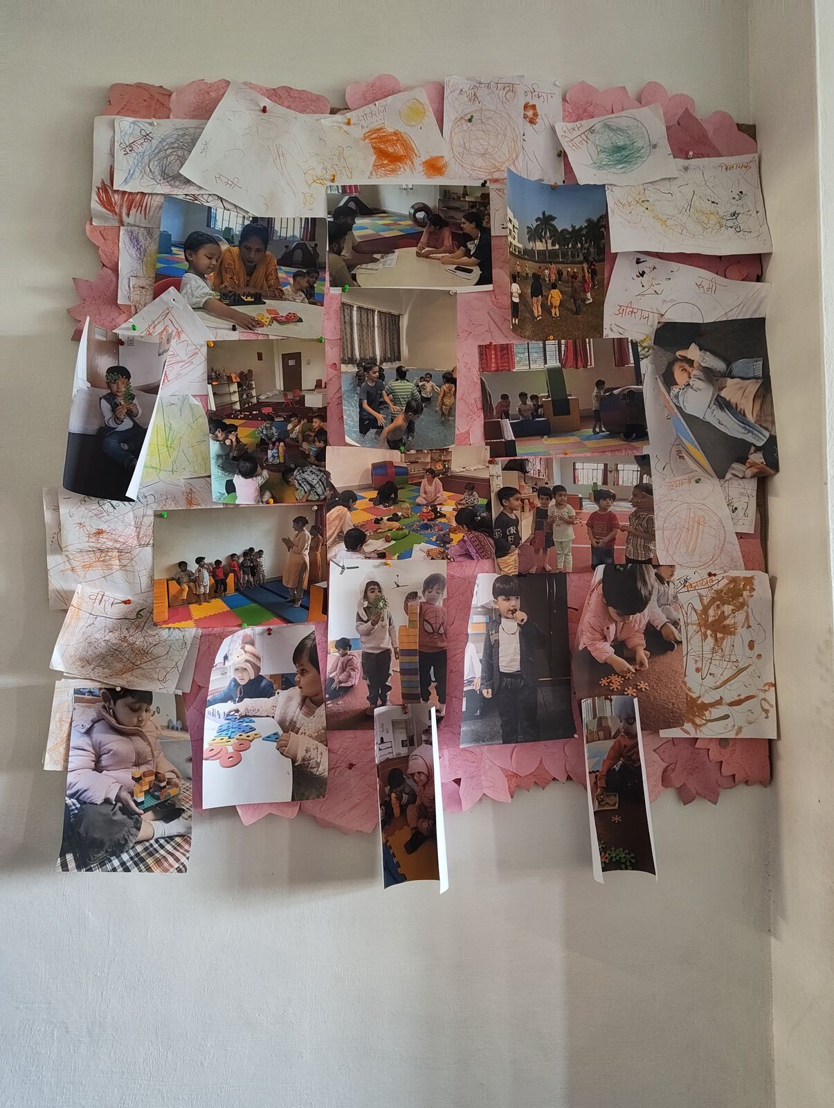 A wall in the classroom covered with photographs of the children and their drawings.